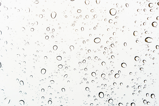 Close up of raindrops on a glass, abstract white background.